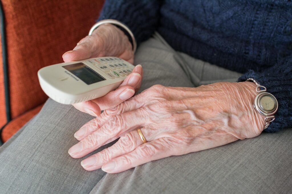 elderly hands in a lap, holding a phone