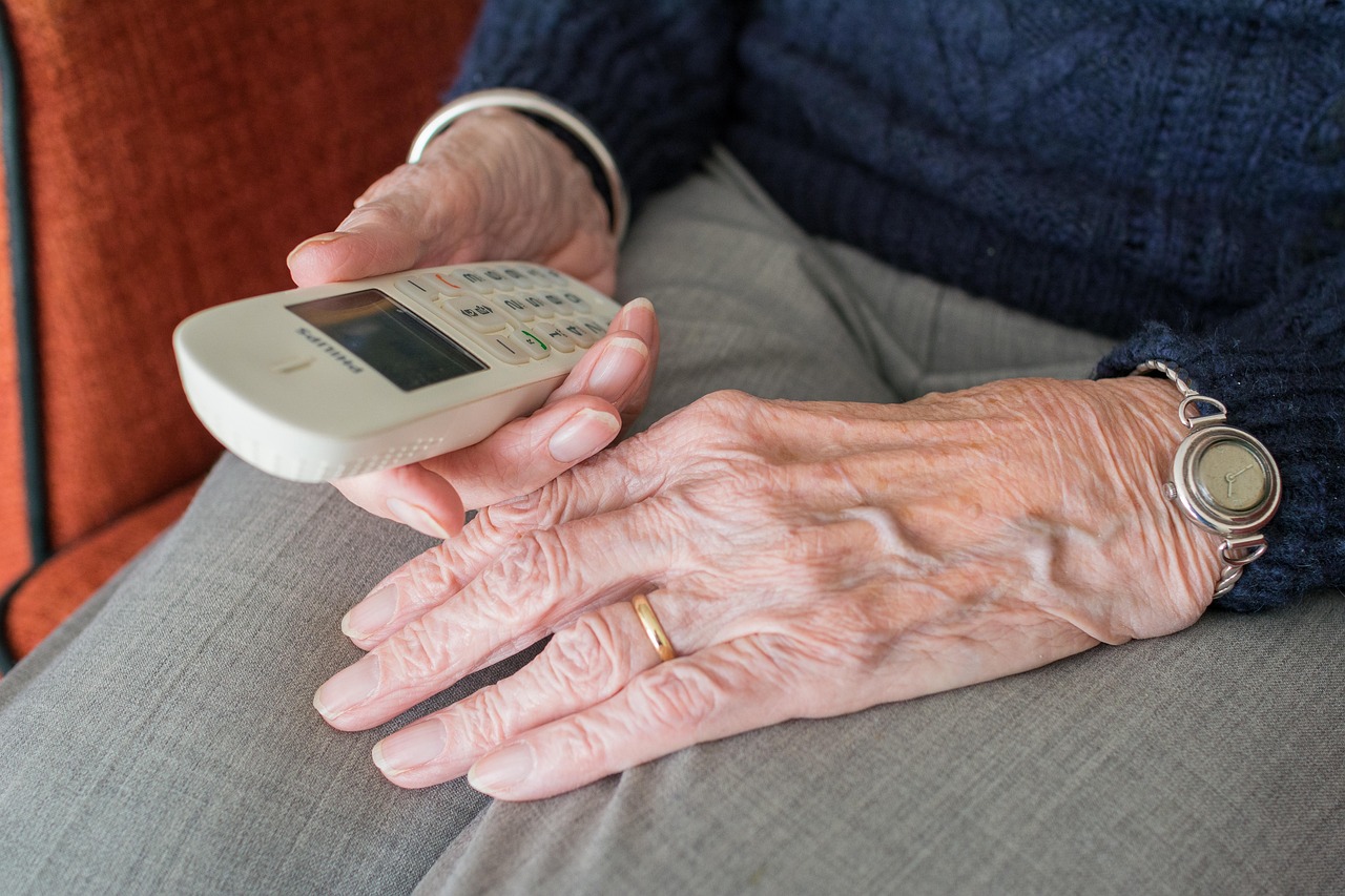 elderly hands in a lap, holding a phone